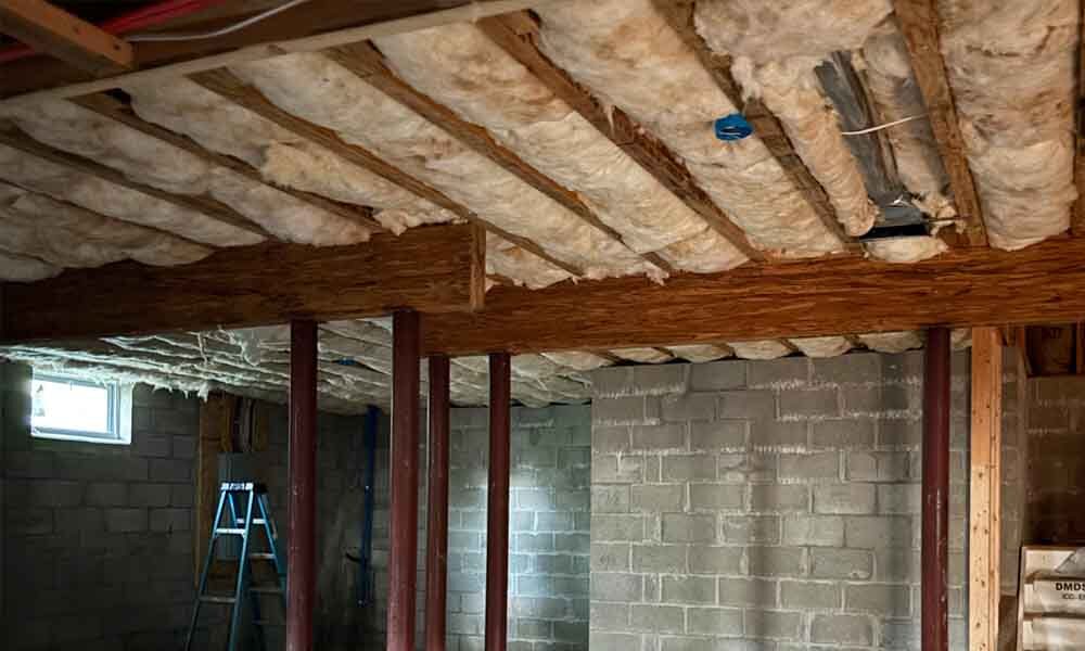 Choose Efficient Insulation for Your Project – Hudson Insulati Fiberglass batt insulation installed in basement ceiling joists above a block foundation wall, single-family home in Brick, NJ, by Hudson Insulation.