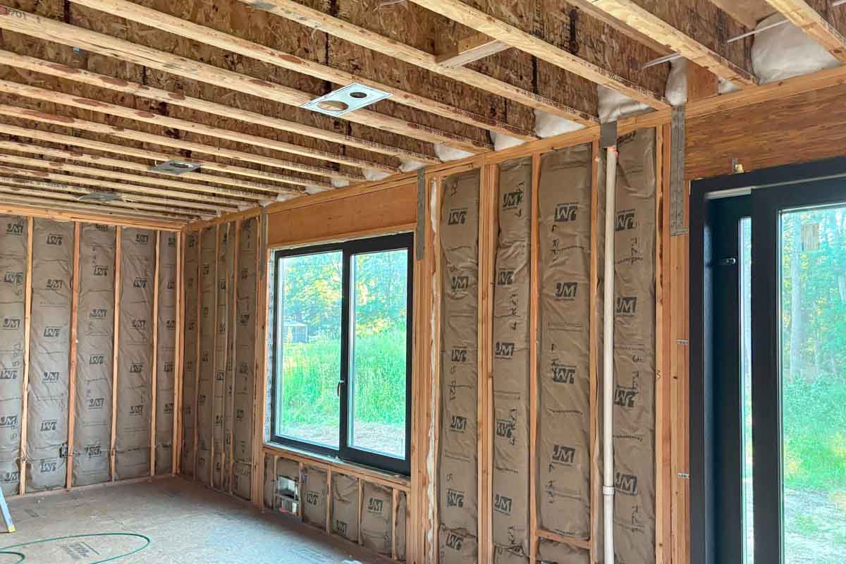 Fiberglass batt insulation in wall cavities around a window and sliding door, single-family home in Brick, NJ, by Hudson Insulation.