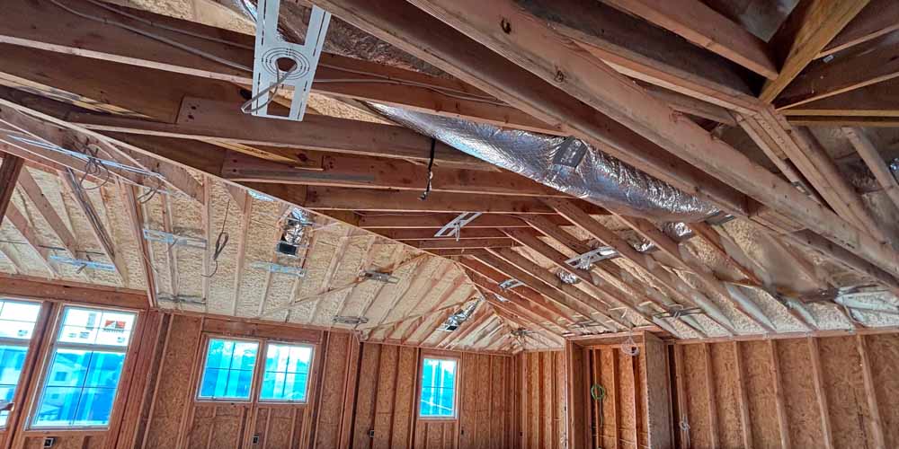 Spray Foam Insulation Wide-angle view of open-cell spray foam insulation on the roof deck of a vaulted, framed ceiling with ductwork, single-family new construction in Point Pleasant, NJ, by Hudson Insulation.