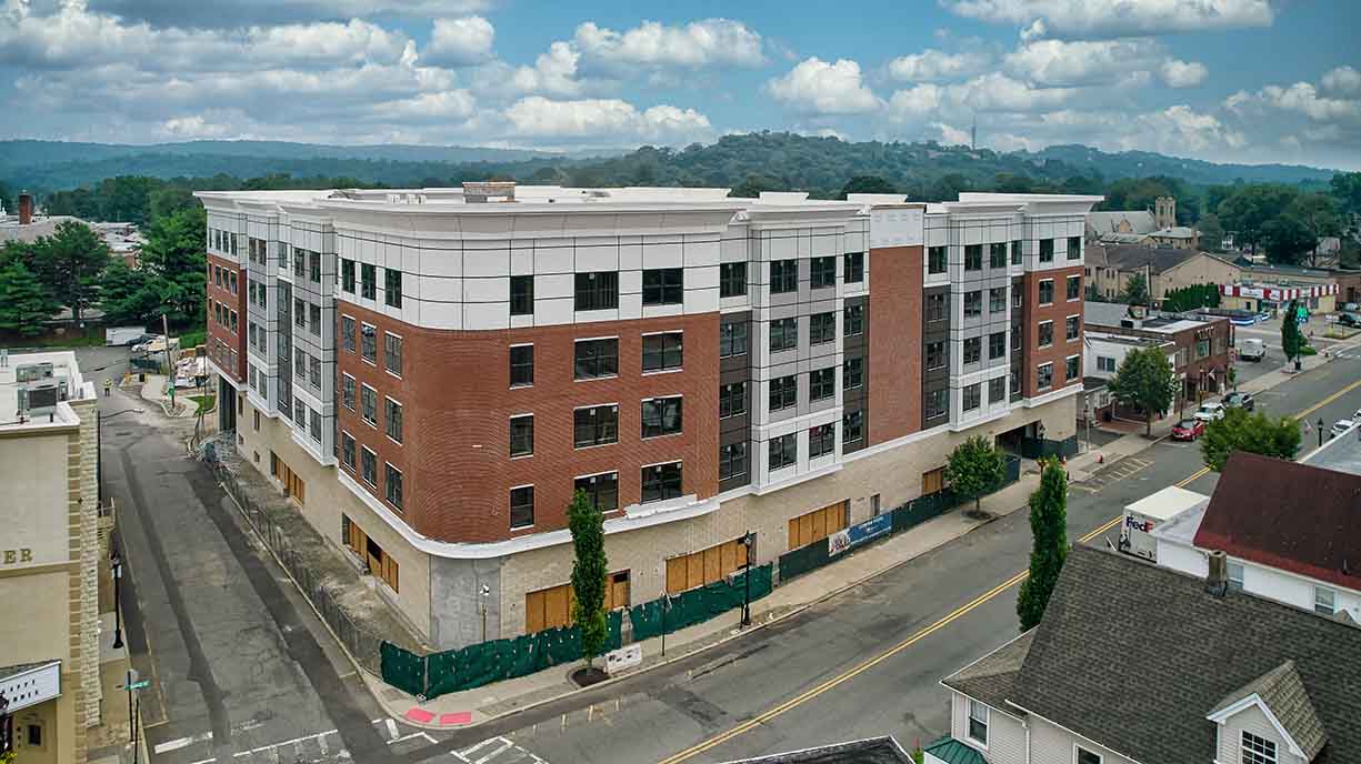 Hudson Insulation commercial new construction project: aerial view of a five-story mixed-use building with brick and panel facade.